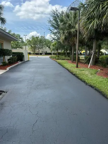 Newly sealed driveway lined with greenery in Cape Coral