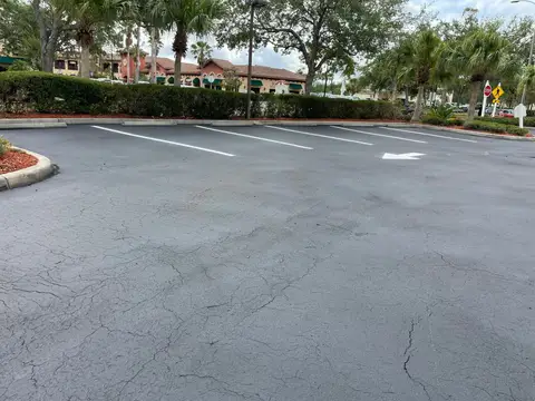 Freshly sealed asphalt area leading to a commercial building